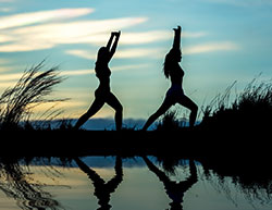 two women in a yoga pose standing outside