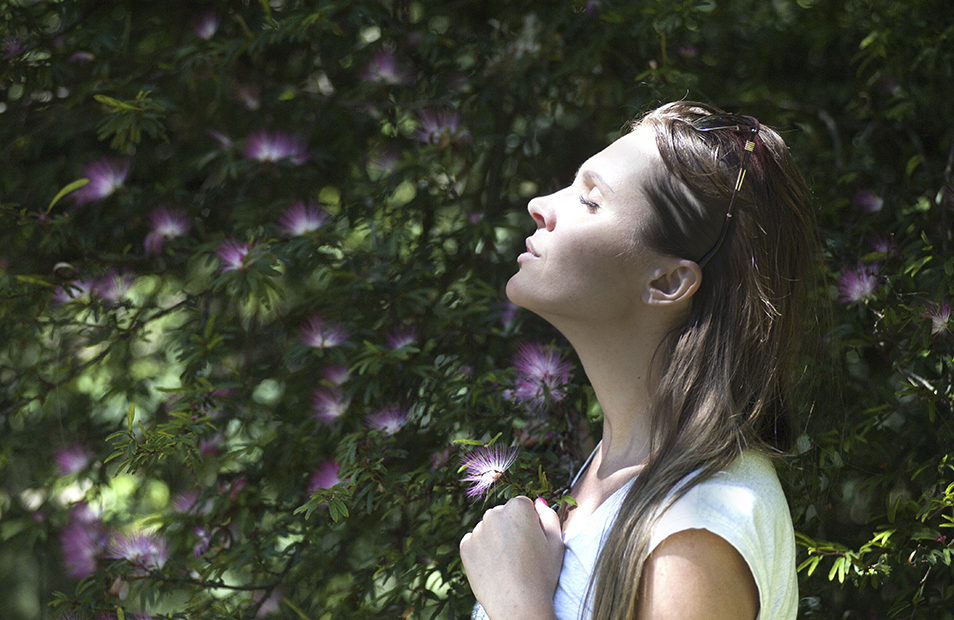 woman wearing white standing outside with her eyes closed